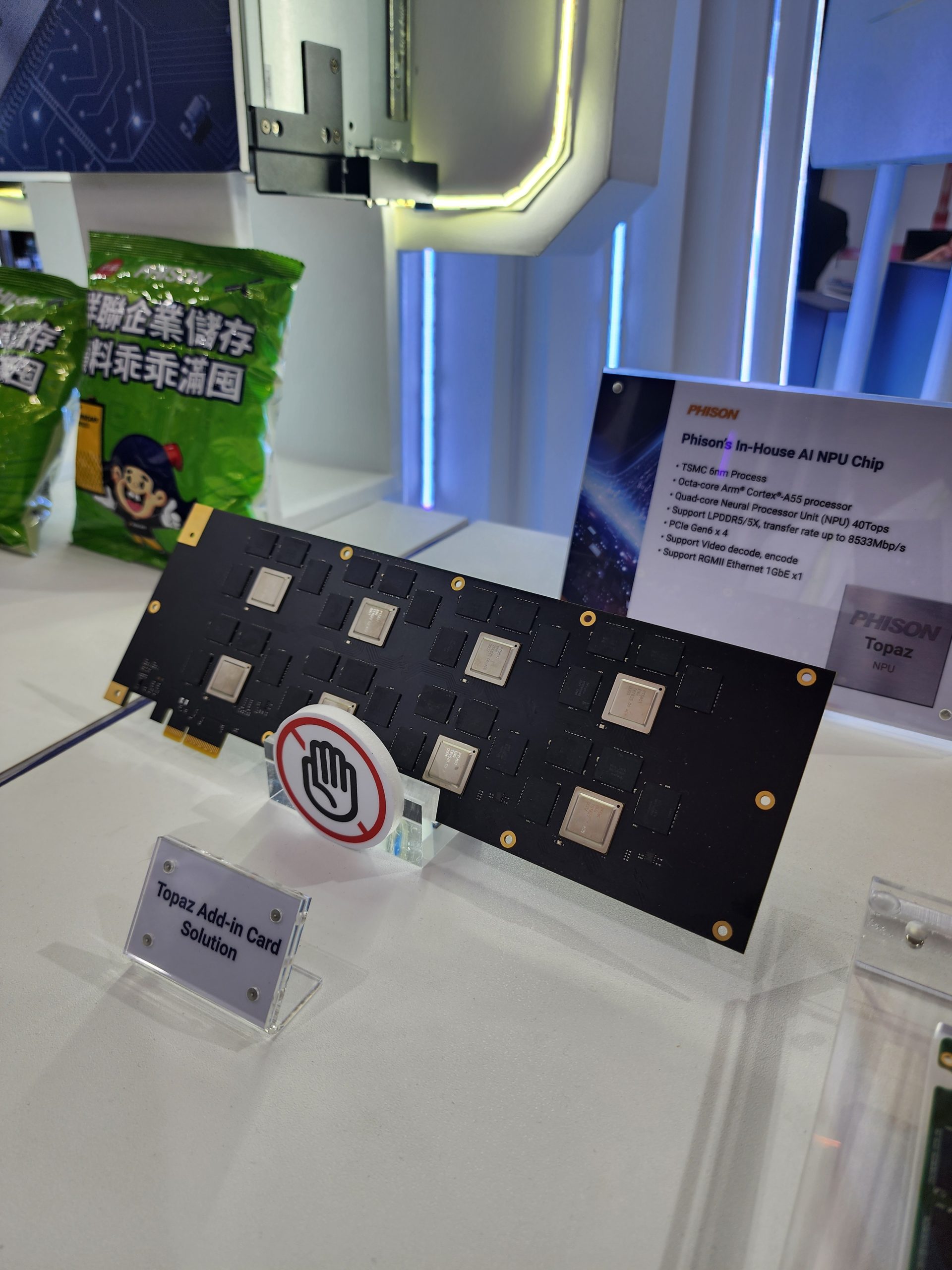 Une puce 'In-House AI NPU Chip' de Phison présentée avec une carte 'Topaz Add-in Card Solution', indiquant des spécifications comme le procédé TSMC 6nm et une puissance de 40 TOPS.