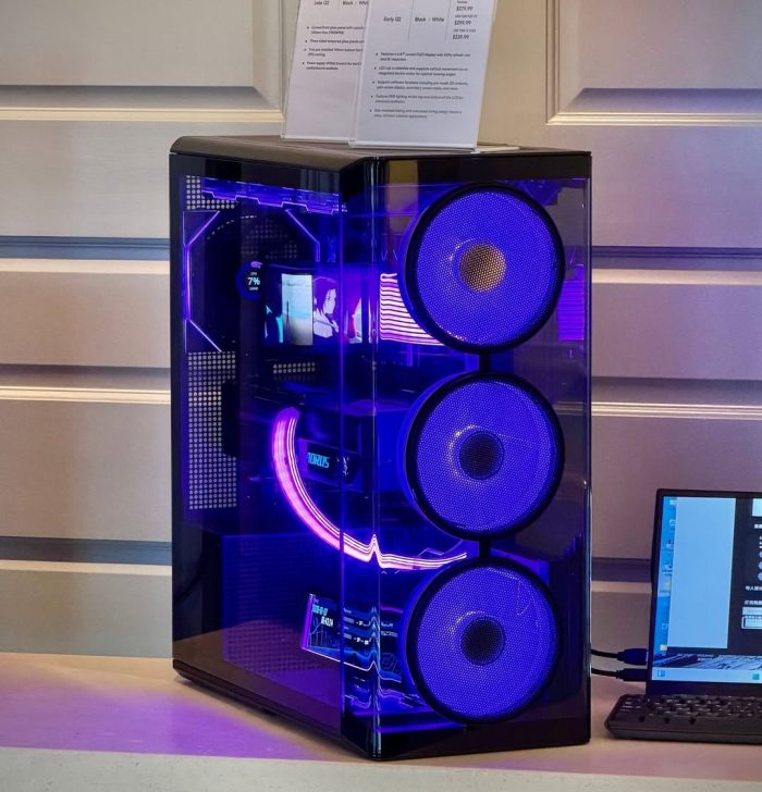 PC gamer sur mesure avec éclairage violet vif et ventilateurs avant proéminents, connecté à un ordinateur portable.