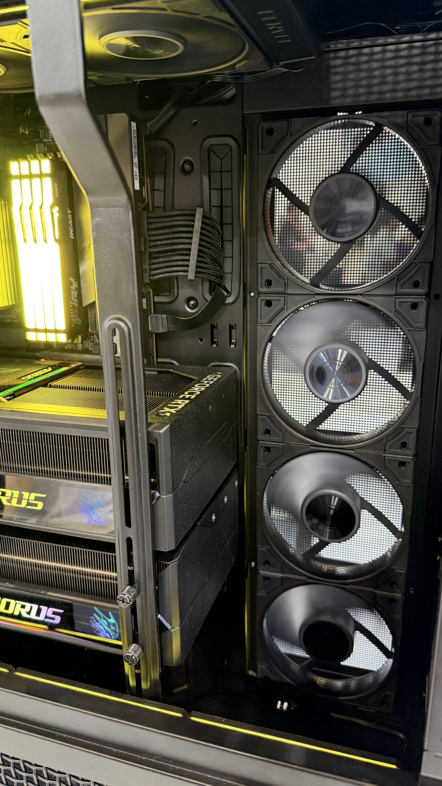 Intérieur d'un boîtier avec une carte graphique Gigabyte AORUS GeForce RTX 4090, des modules RAM illuminés et trois grands ventilateurs.