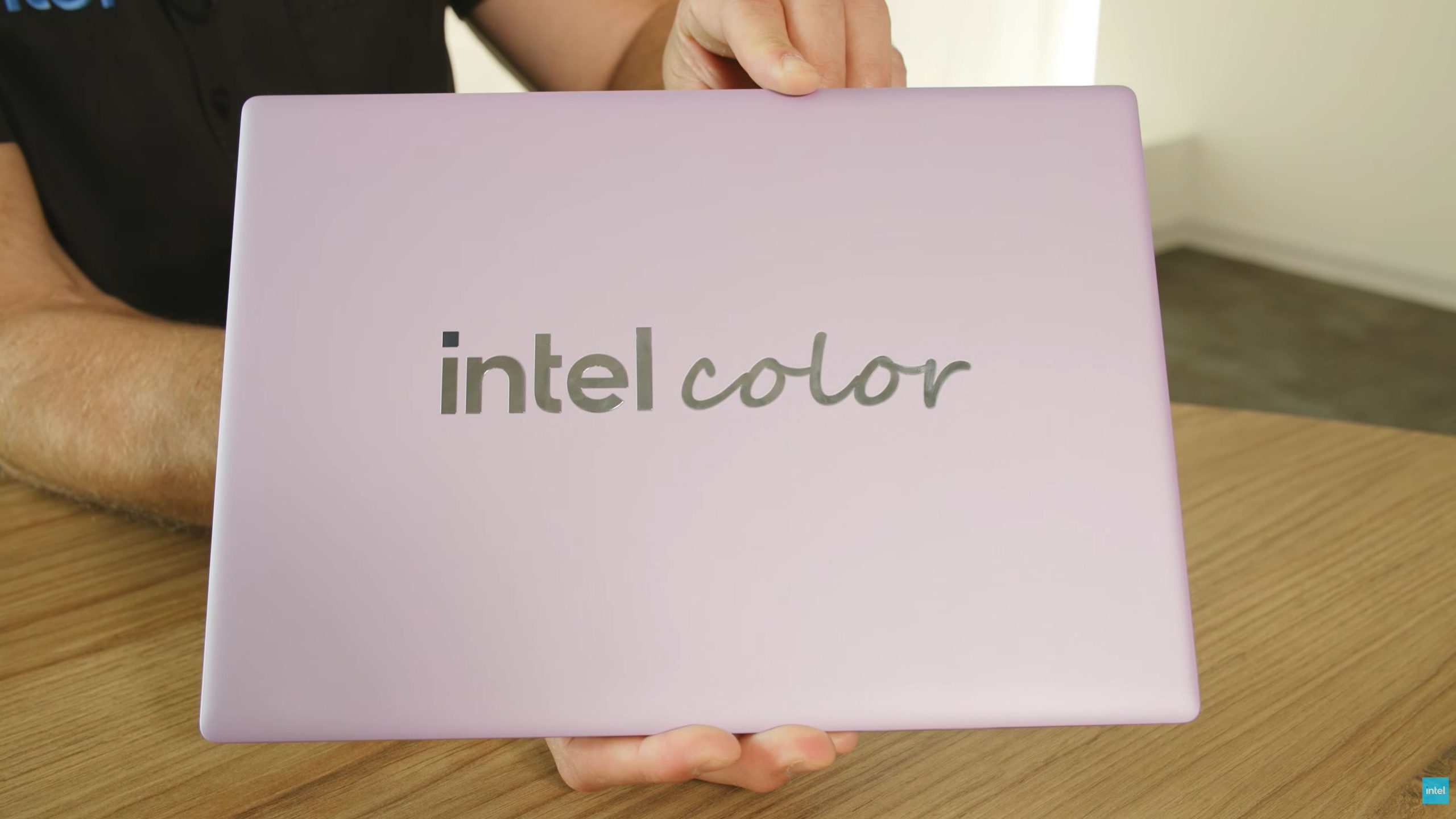 Une personne tient un ordinateur portable couleur lavande avec le texte 'intel color' sur le couvercle.