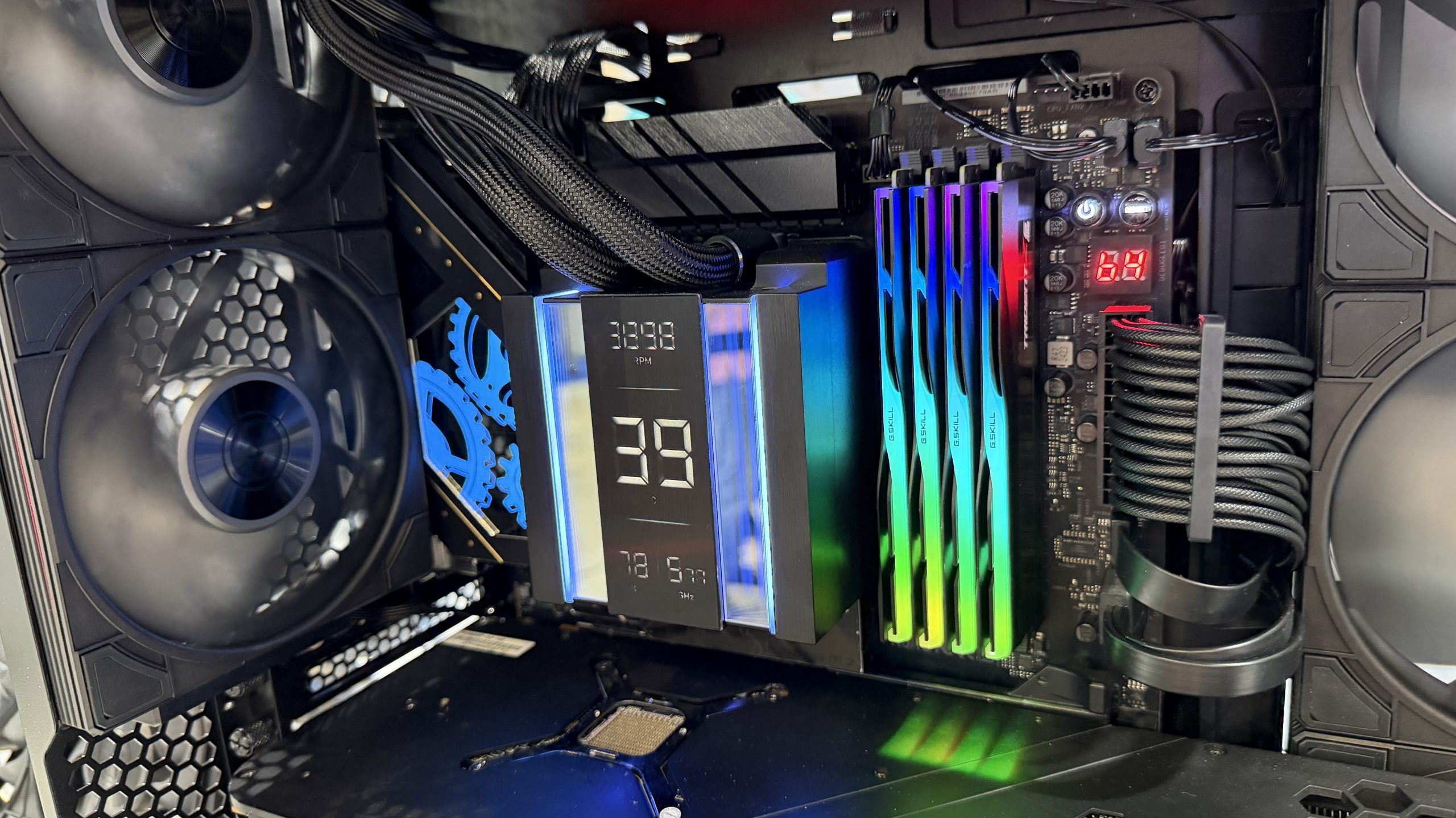 Un PC sur mesure avec un système de refroidissement affichant '3988 RPM', des modules RAM RGB G.Skill et deux ventilateurs noirs.