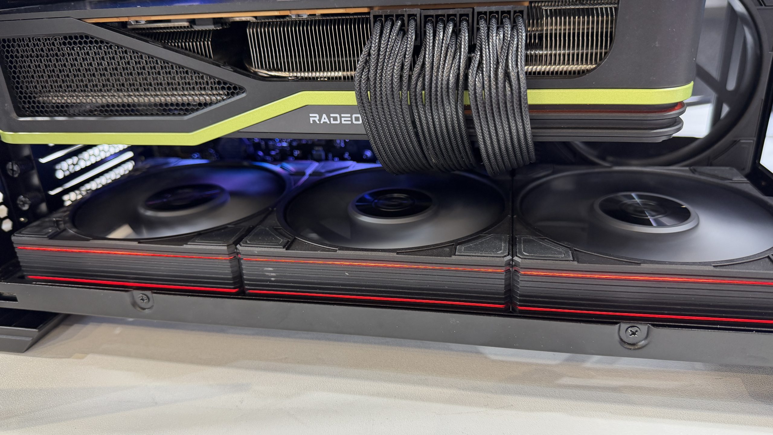 Une carte graphique AMD Radeon installée dans un boîtier d'ordinateur, avec plusieurs ventilateurs et des câbles d'alimentation visibles.