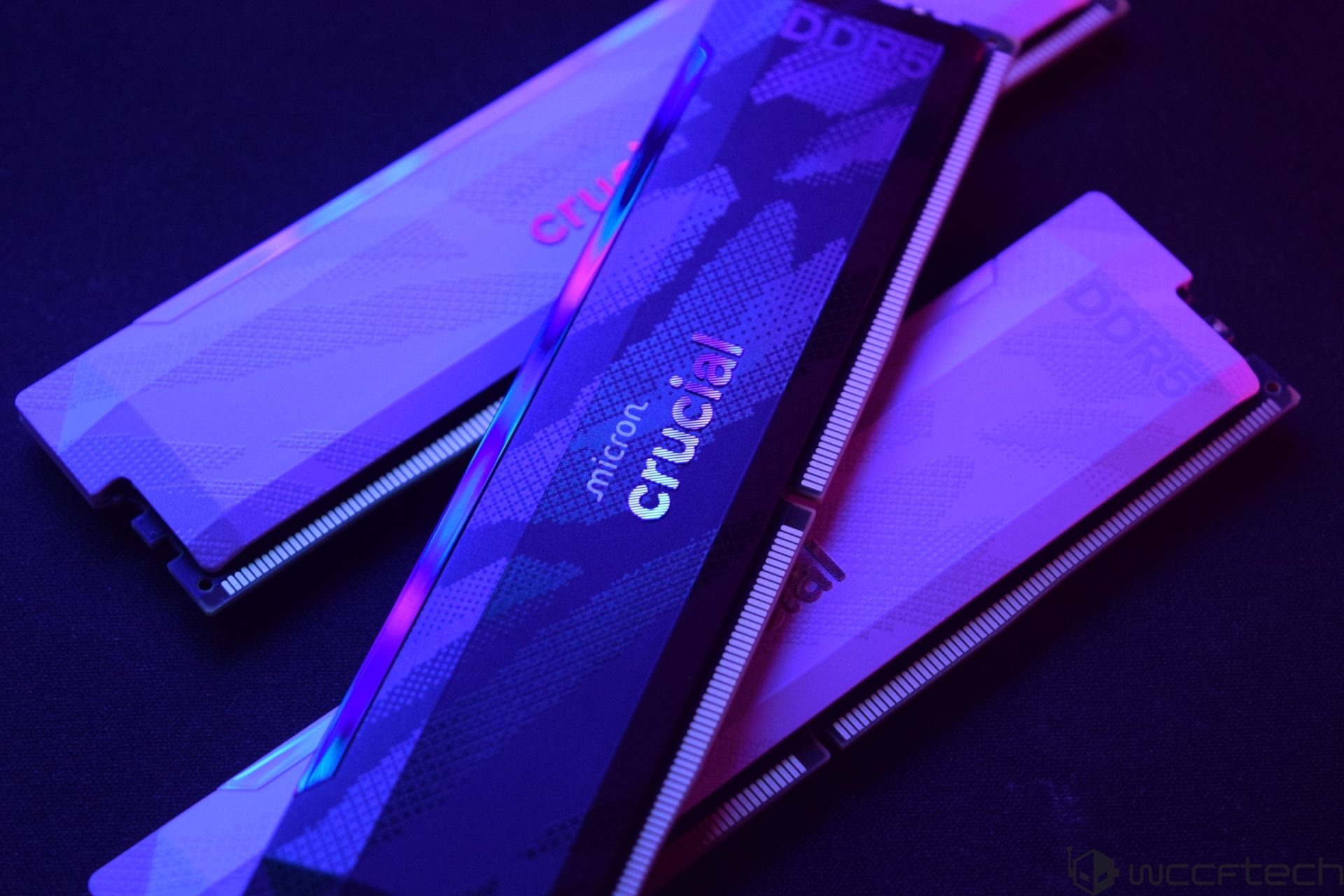 Trois barrettes de RAM Crucial DDR5 avec le logo Micron, éclairées en violet et bleu.