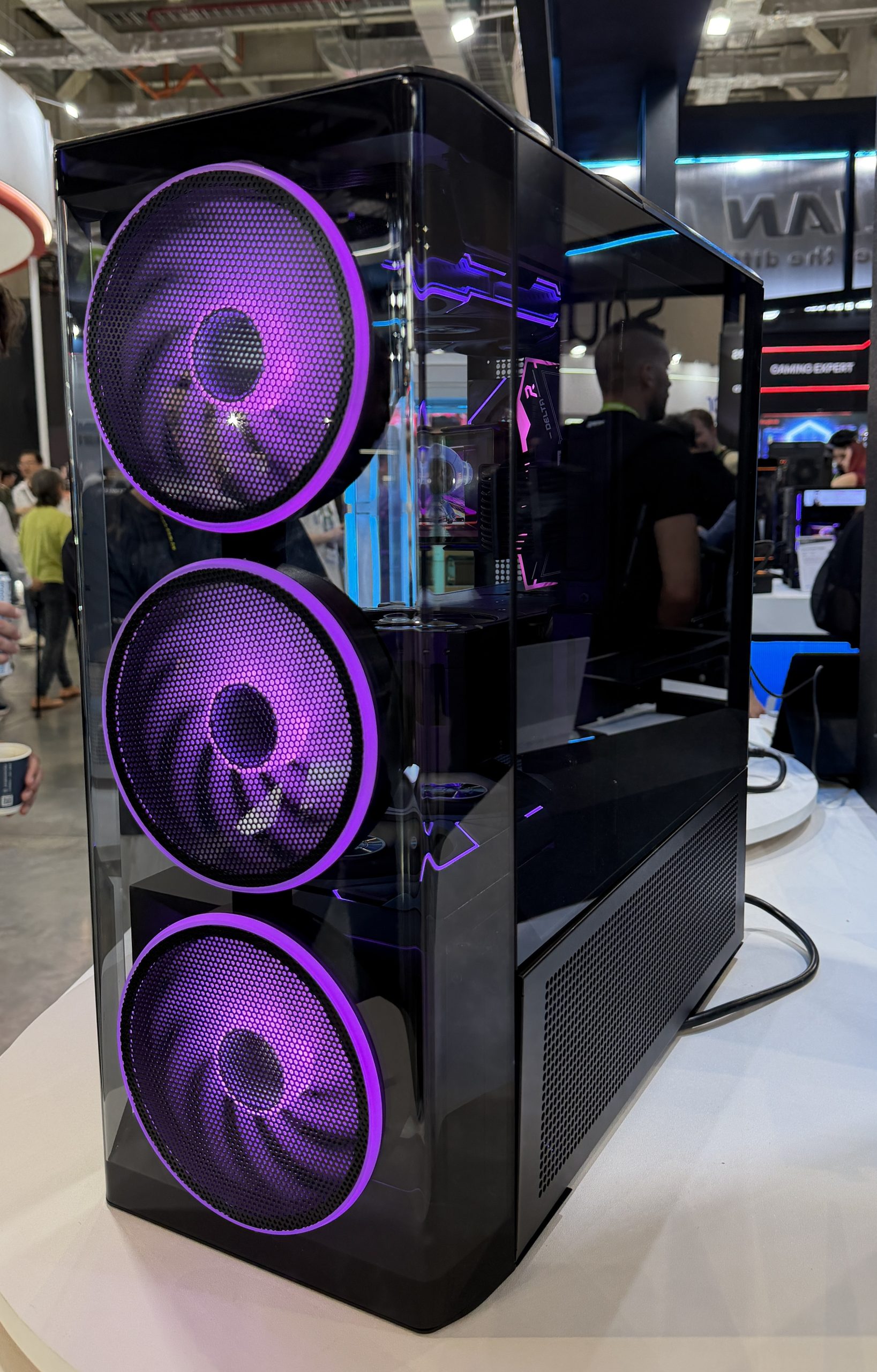 PC gamer sur mesure avec un boîtier transparent équipé de trois grands ventilateurs LED violets, exposé sur un salon.