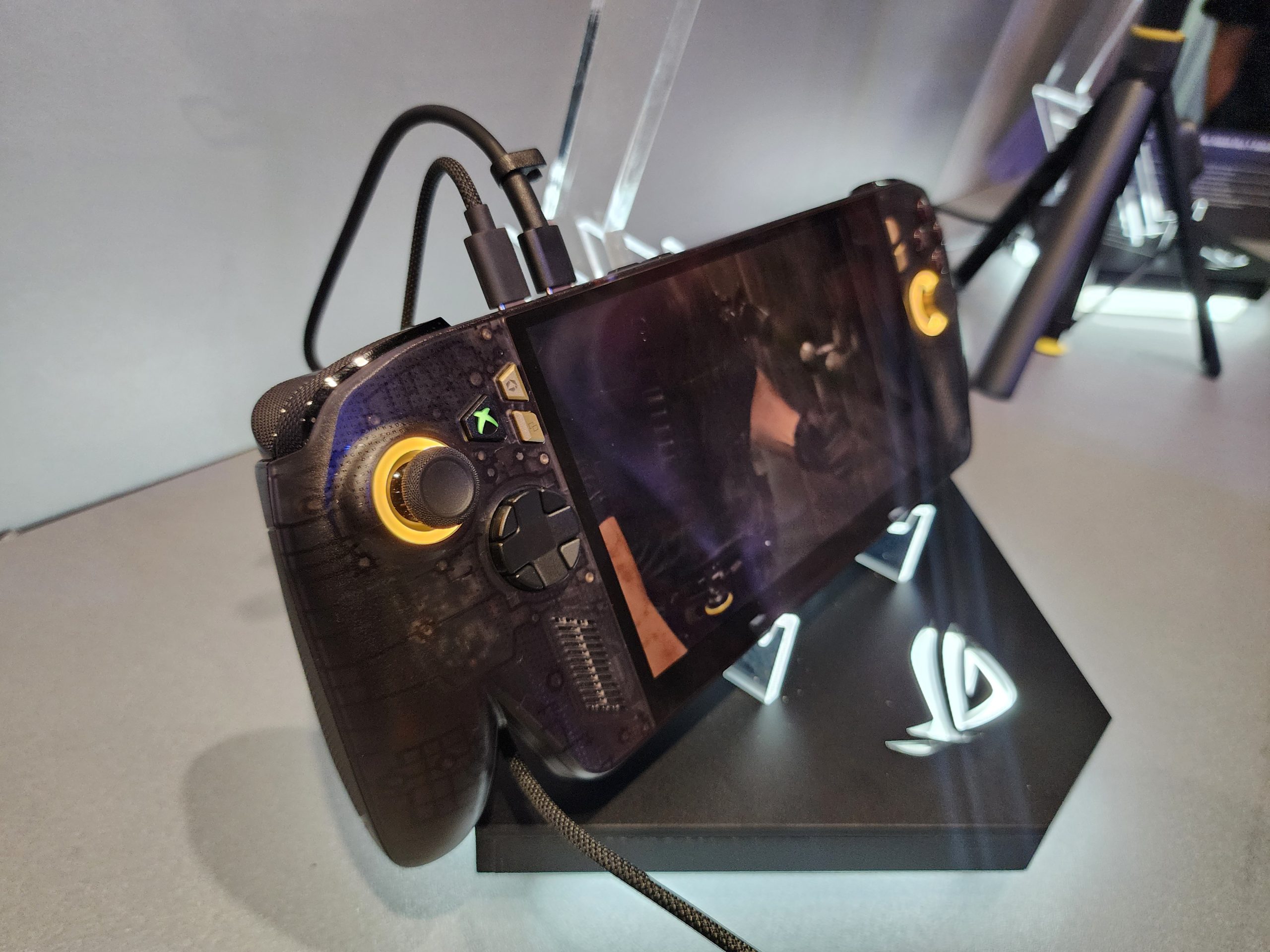 Une console portable ASUS ROG Ally présentée sur un support avec ses boutons rétroéclairés.
