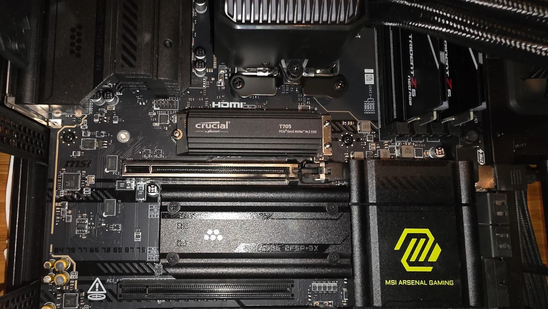 Intérieur d'un PC montrant un SSD NVMe Crucial T700 installé sur une carte mère MSI.