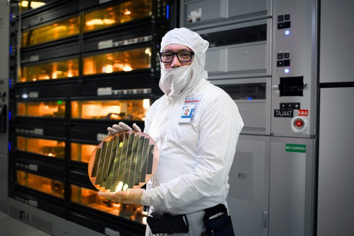 Un employé d'Intel tenant une galette de silicium utilisant la technologie Foveros 3D dans une usine.