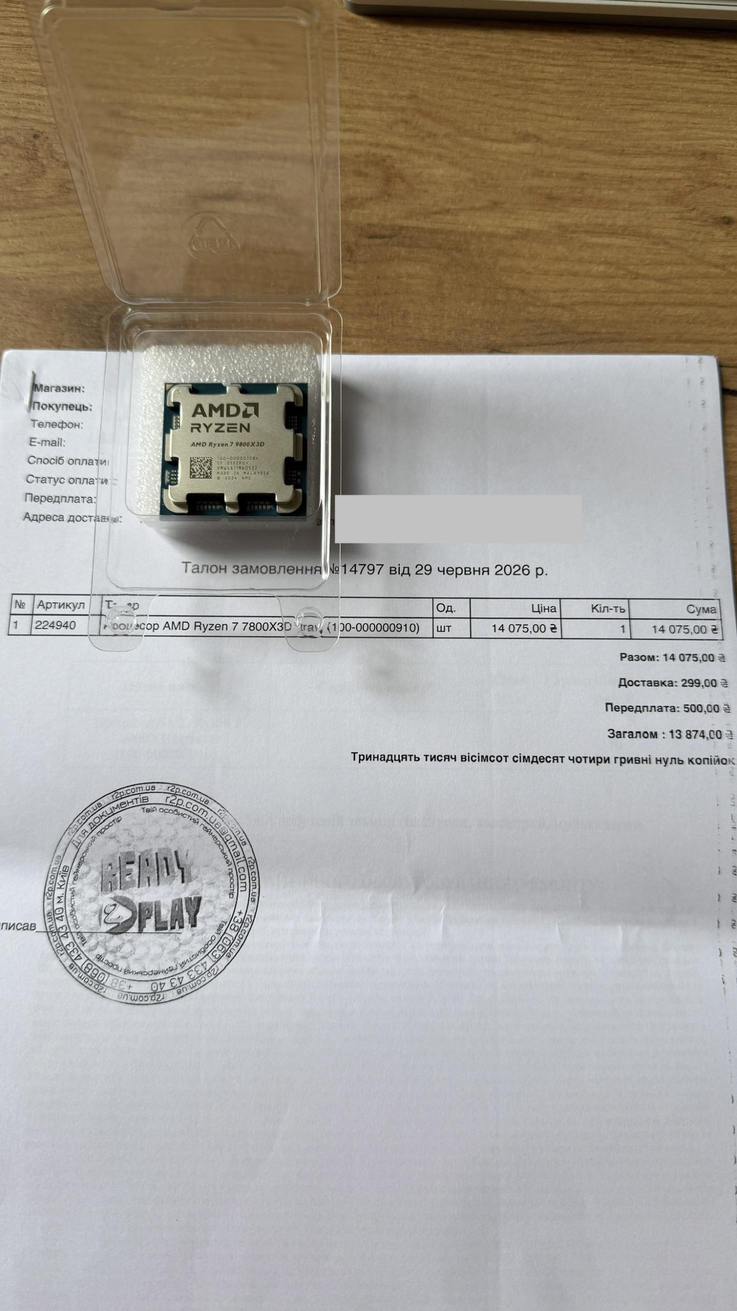 Un processeur AMD Ryzen 7 7800X3D dans son boîtier transparent, posé sur un bon de commande portant le même numéro de modèle.