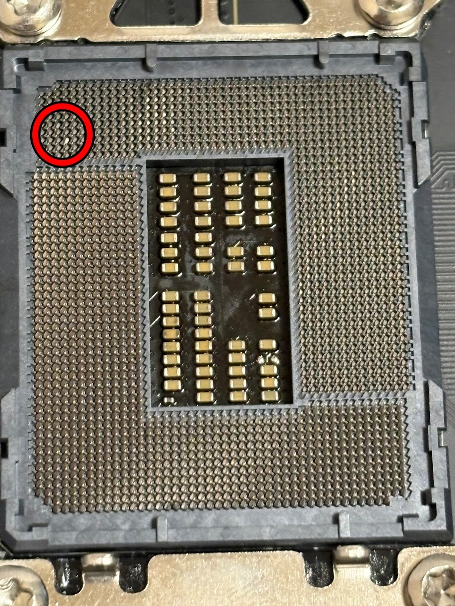 Un socket CPU sur une carte mère avec un pin tordu entouré en rouge.
