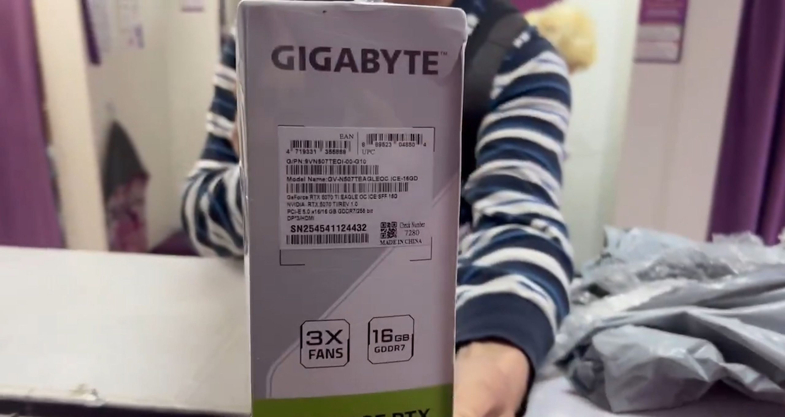 Une personne tenant une boîte de la carte graphique Gigabyte GeForce RTX 5070 Ti Eagle, avec des étiquettes indiquant '3X FANS' et '16GB GDDR7.'