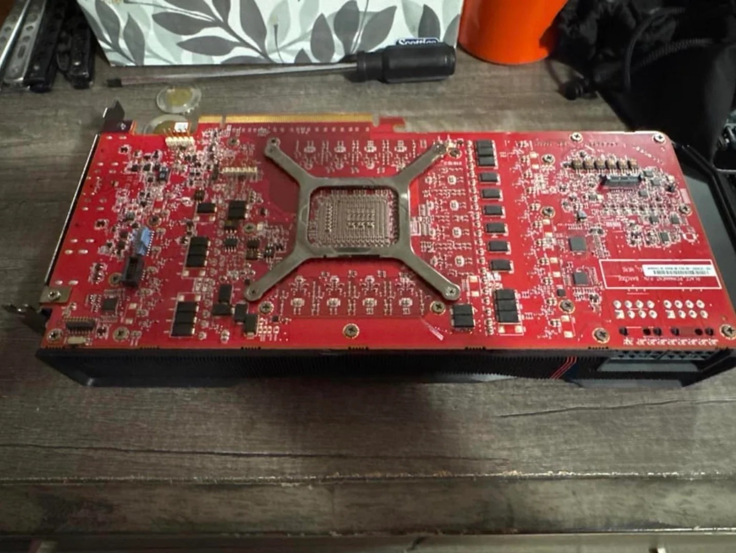 Vue d'ensemble d'une carte graphique rouge sans marque, posée sur une table en bois.