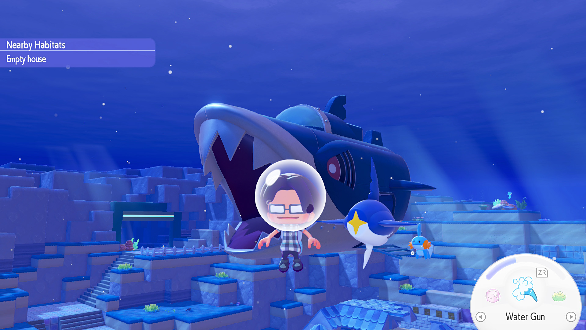 Dans 'Min-Aquarium', un personnage en combinaison spatiale flotte sous l'eau près d'un énorme sous-marin en forme de poisson, avec un menu affichant 'Water Gun'.