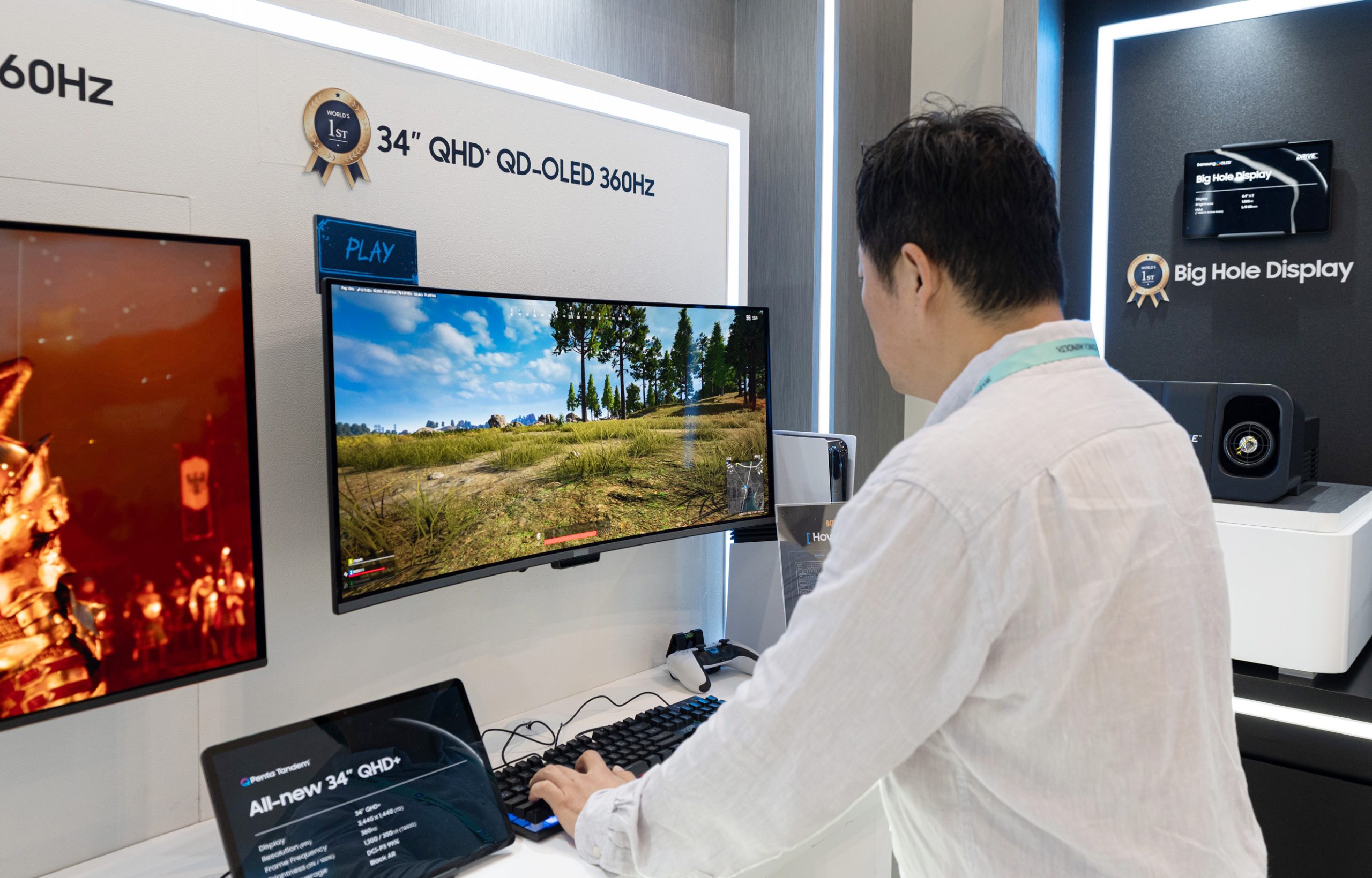Une personne utilise un moniteur 34 pouces QHD+ QD-OLED 360Hz sur lequel s’affiche un jeu. Une tablette en dessous indique 'All-new 34 QHD+'.