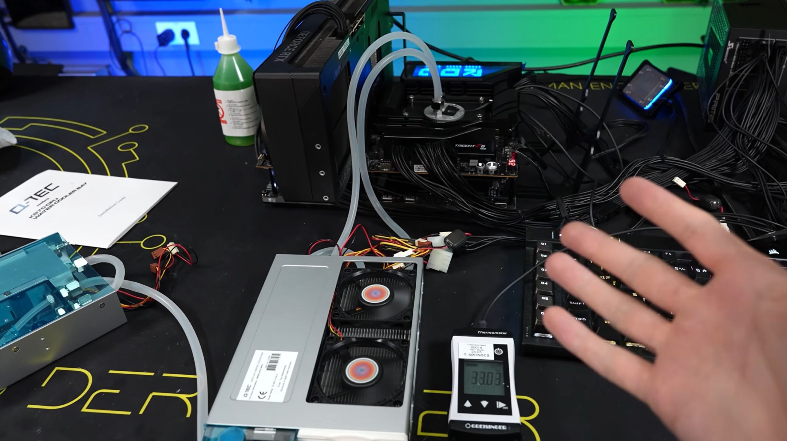 Un banc de test avec un refroidissement liquide, une carte graphique NVIDIA GeForce RTX et des composants DEEPCOOL. Un thermomètre affiche 38.03°C.