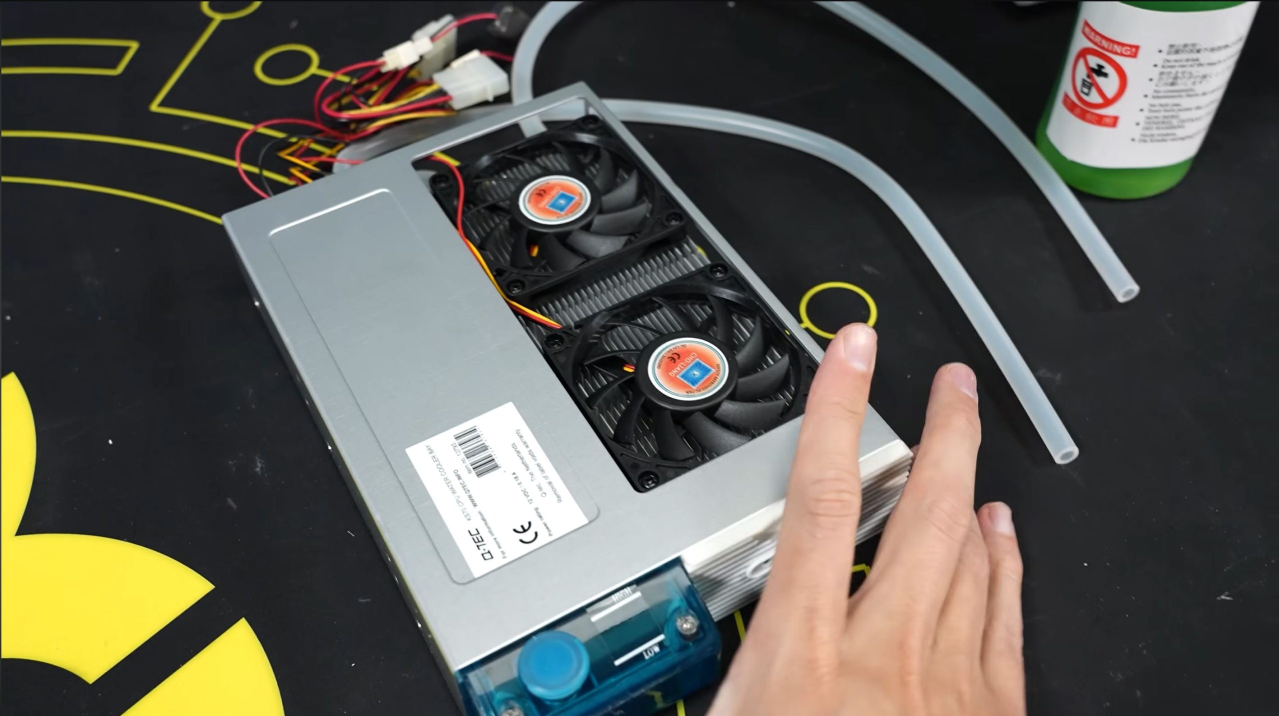Un bloc d'alimentation Q-Tec 500W avec un refroidissement à double ventilateur, entouré de câbles et de tubes sur une surface sombre.