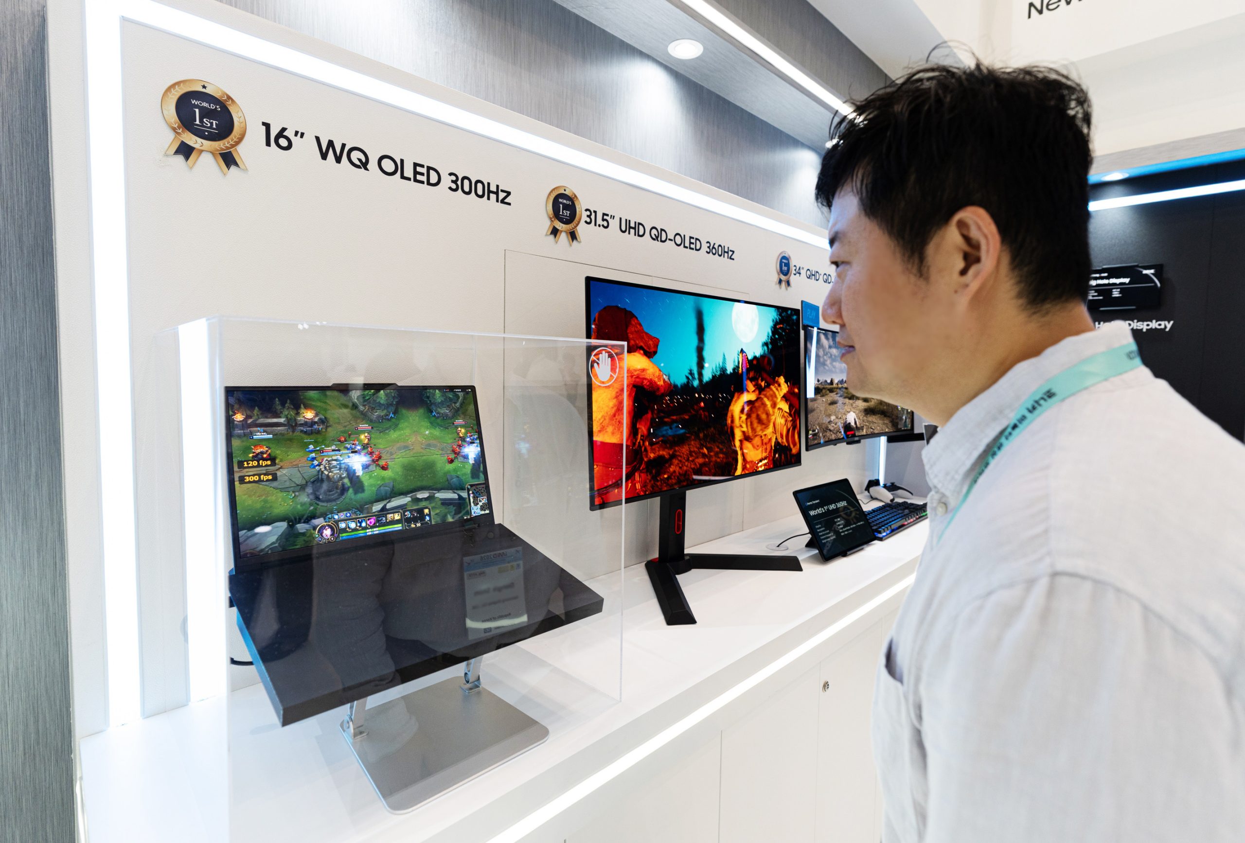 Un écran de 16 pouces WQ OLED 300Hz affiche un jeu vidéo. On aperçoit également d’autres moniteurs étiquetés 31,5 pouces UHD QD-OLED 360Hz et 34 pouces GHD QD-OLED.
