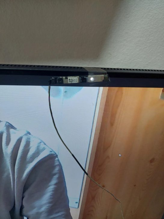 Une installation de fortune d'une webcam fixée sur un moniteur, affichant un appel vidéo.