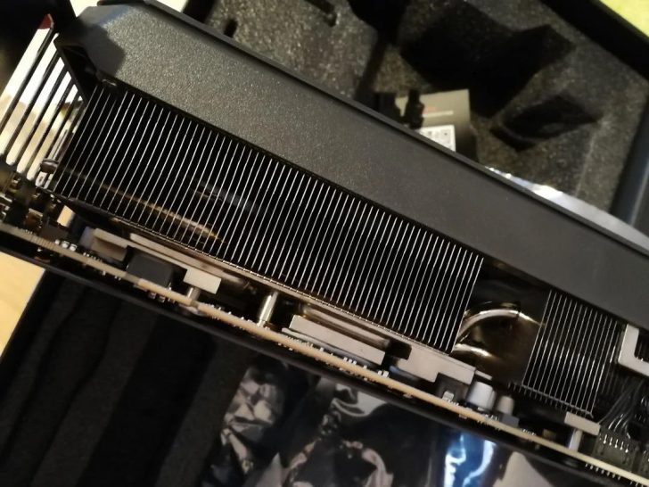 Une vue rapprochée d'une carte graphique non marquée avec ses ailettes de refroidissement et ses heatpipes exposés, dans un boîtier matelassé.