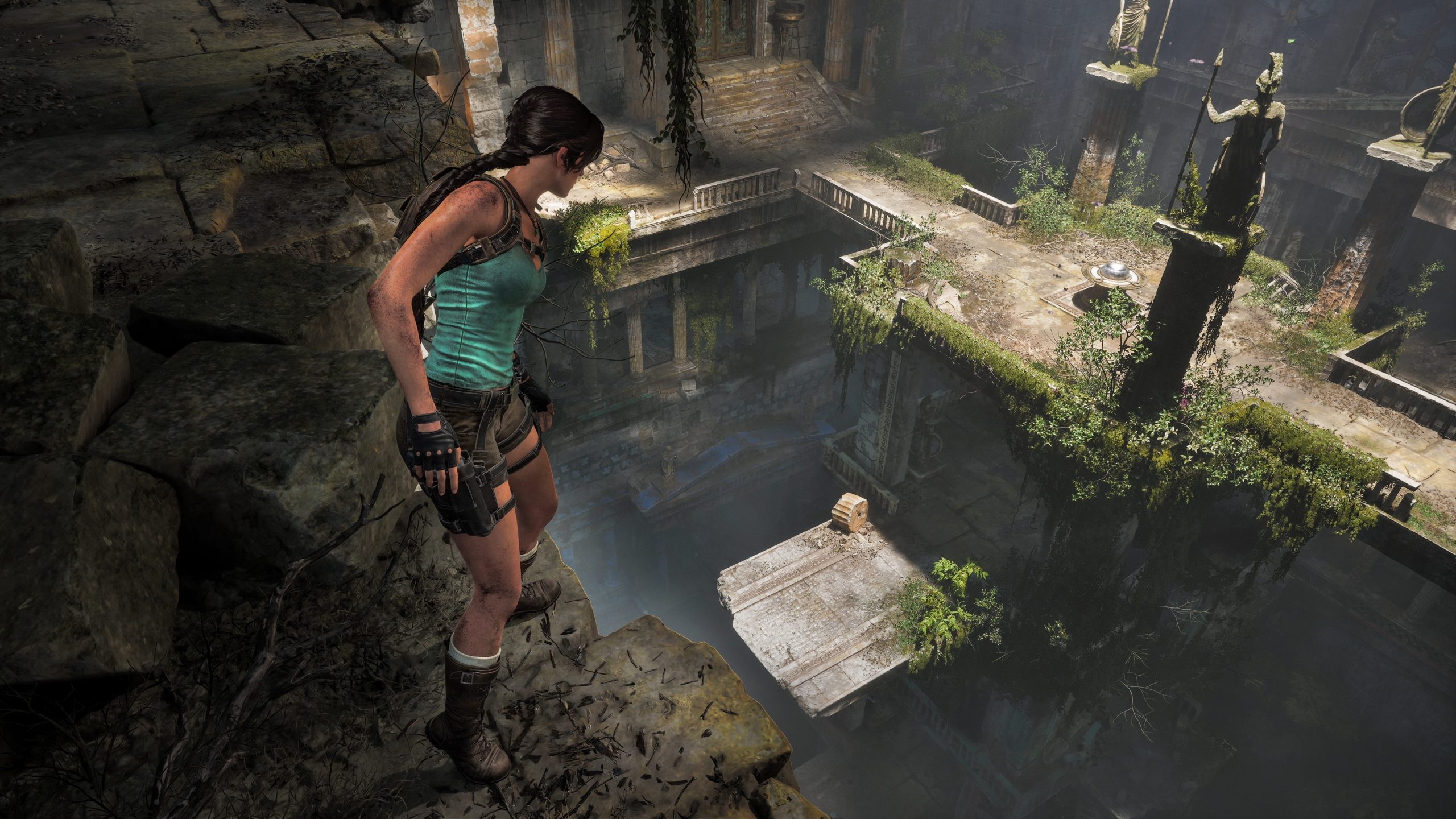 Lara Croft observe des ruines antiques couvertes de mousse depuis une corniche.