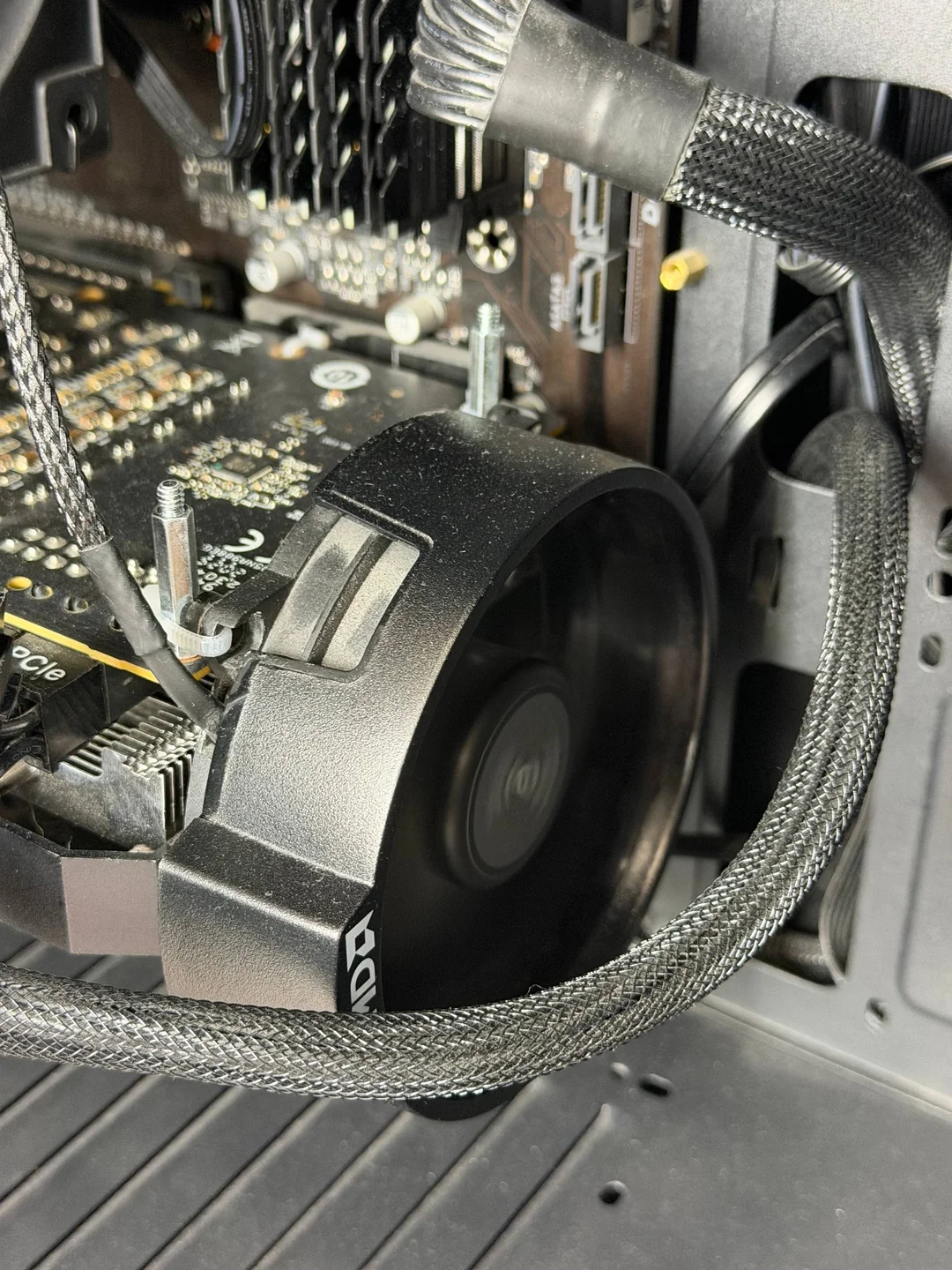 Un ventilateur de refroidissement AMD d'origine est installé dans un boîtier PC, avec des câbles tressés et une carte graphique visibles.