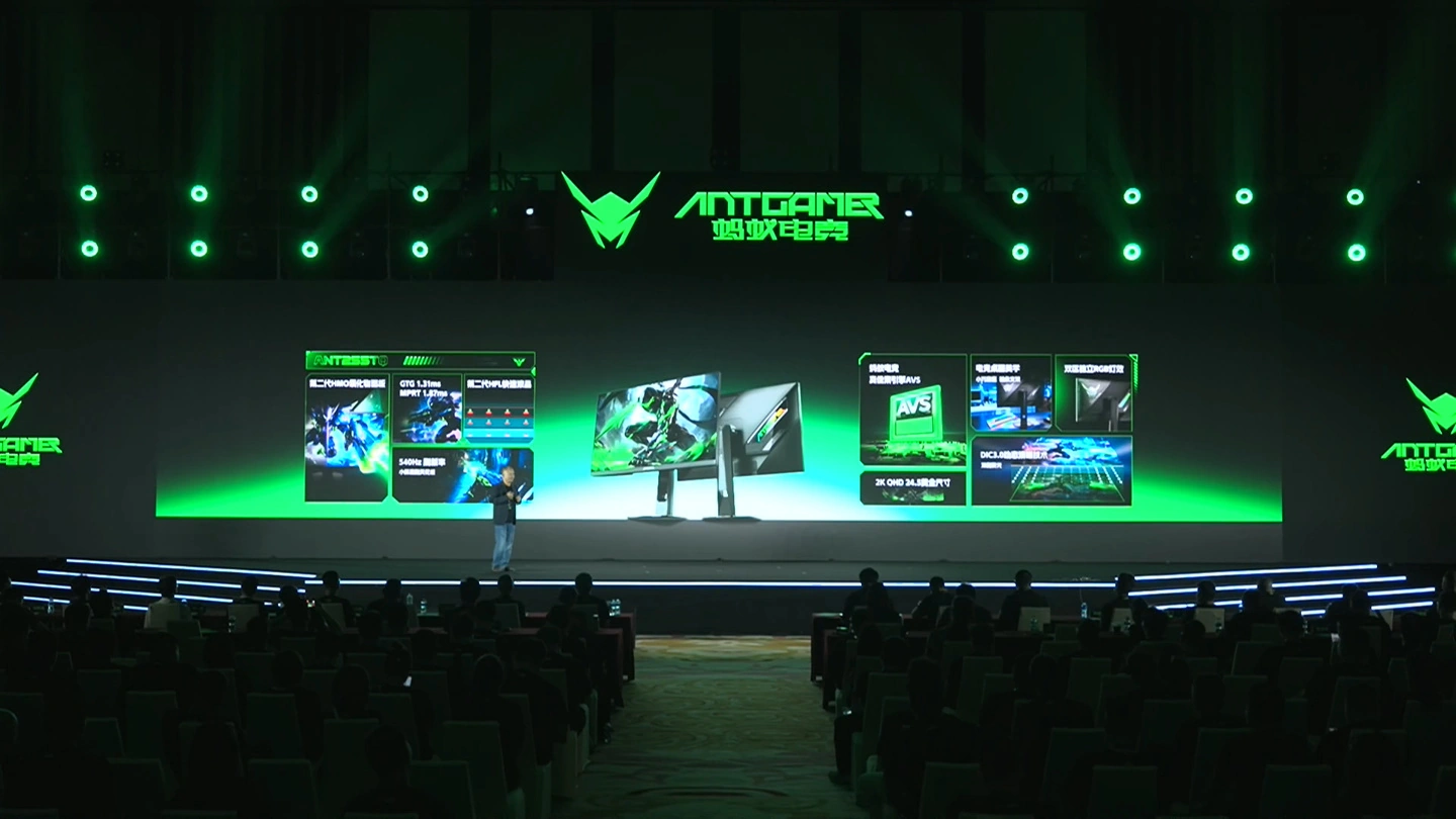 A presenter on stage showcasing Antgamer monitors with features like 'GTG 1.1ms,' '540nits,' and 'AVS.'