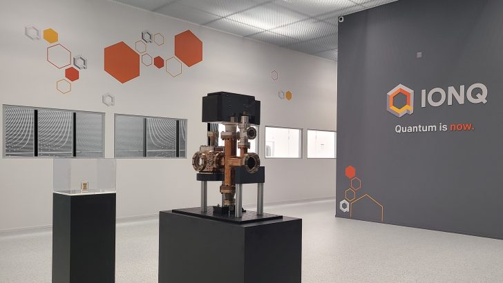 Une salle avec la marque IonQ présentant du matériel de calcul quantique sur un podium noir.