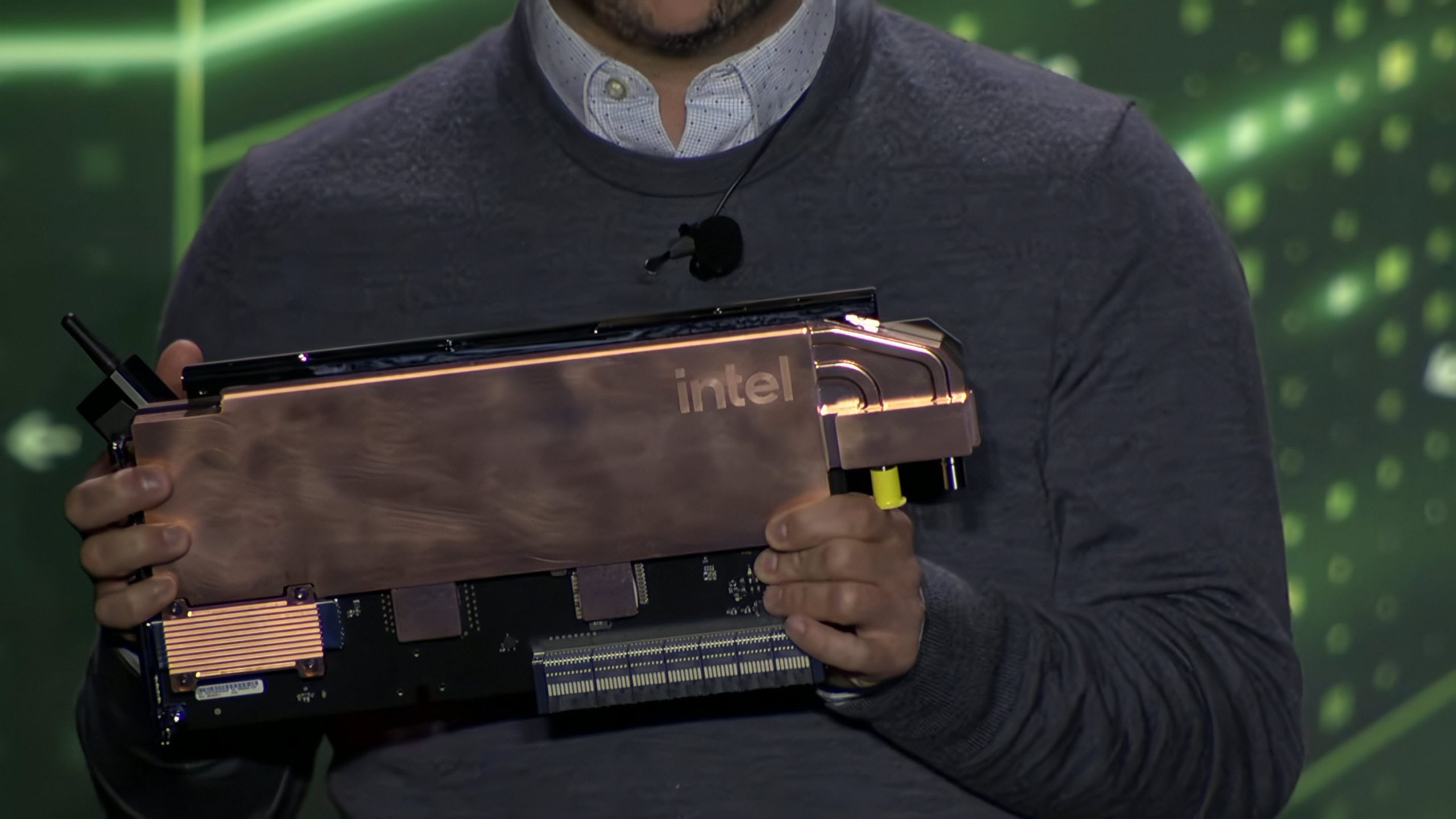 Un présentateur tenant une carte accélératrice Intel avec un radiateur en cuivre visible et le logo Intel.