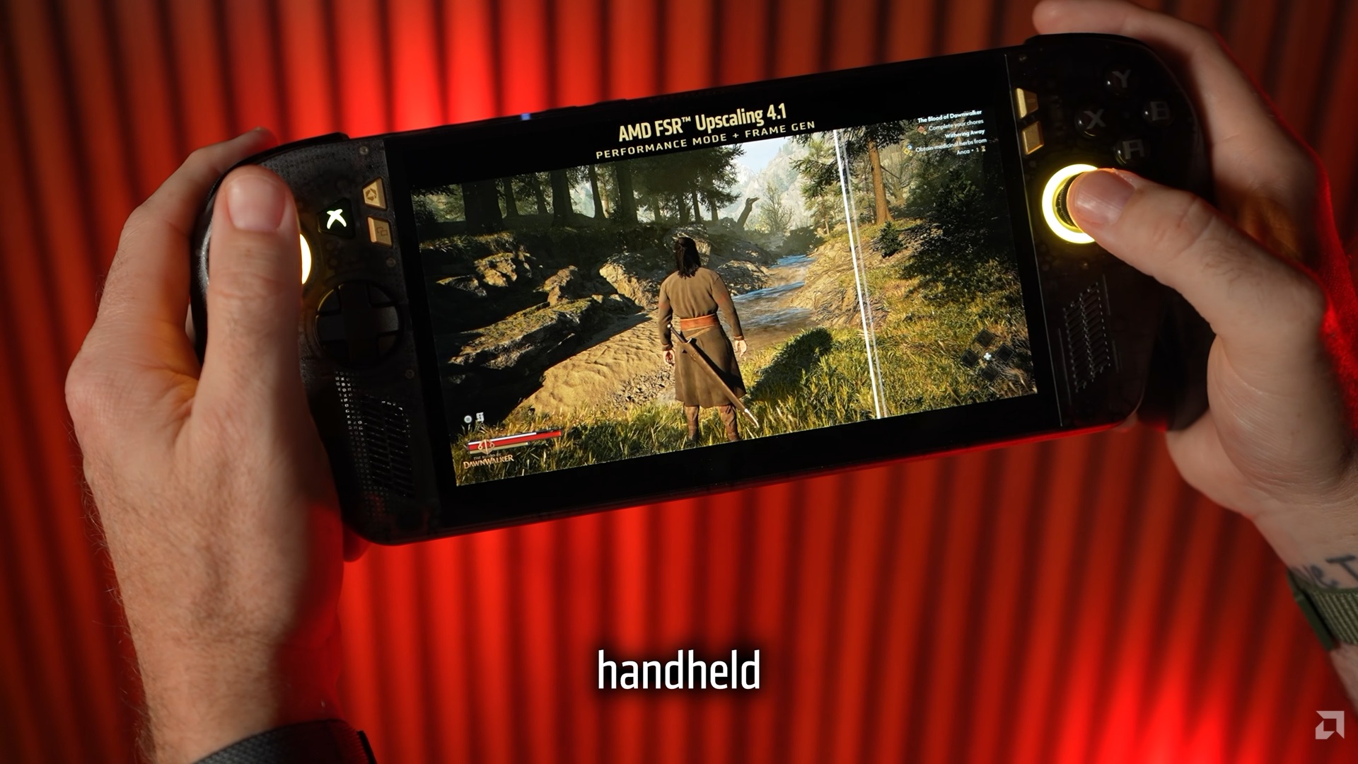 Une personne tient un PC gaming portable affichant un personnage explorant une forêt dans un jeu, avec les textes 'AMD FSR™ Upscaling 4.1' et 'PERFORMANCE MODE + FRAME GEN' visibles à l'écran.