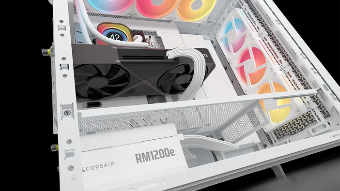 Une alimentation Corsair RM1200e et une carte graphique NVIDIA RTX à l'intérieur d'un boîtier de bureau blanc avec éclairage RGB et des tuyaux de watercooling visibles.