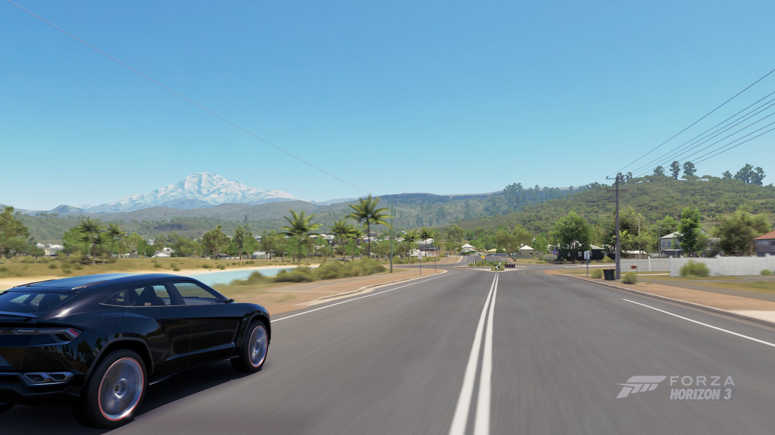 Une voiture roule sur une route rurale dans Forza Horizon 3, avec des montagnes en arrière-plan.