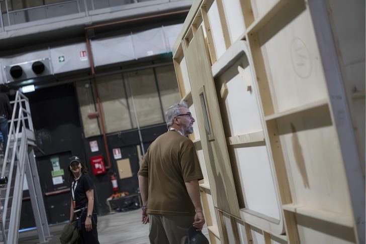 Deux personnes dans un environnement industriel, l'une examinant de près la structure en bois d'un mur.