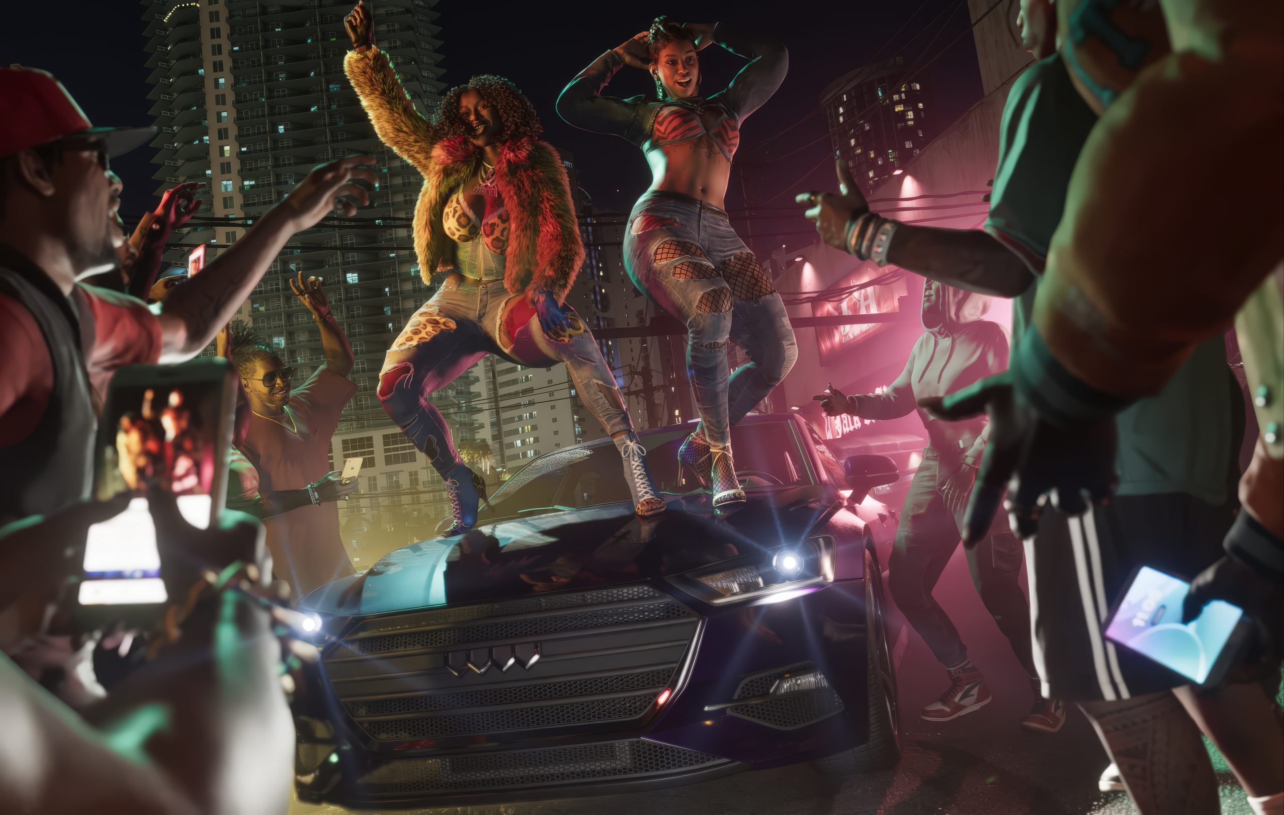 Une scène de 'Grand Theft Auto VI' montre deux personnages dansant sur le capot d'une voiture dans un décor urbain néon, entourés de passants filmant la scène avec leurs smartphones.