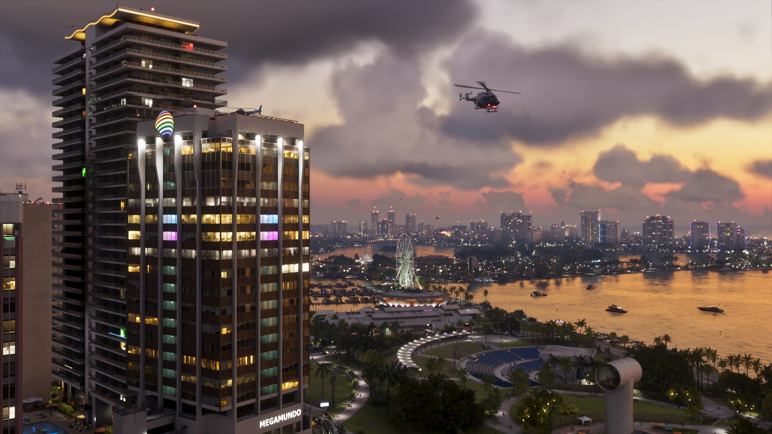 Un hélicoptère survole une ville au coucher du soleil, avec un bâtiment 'MEGAMUNDO' et une grande roue visibles en arrière-plan.