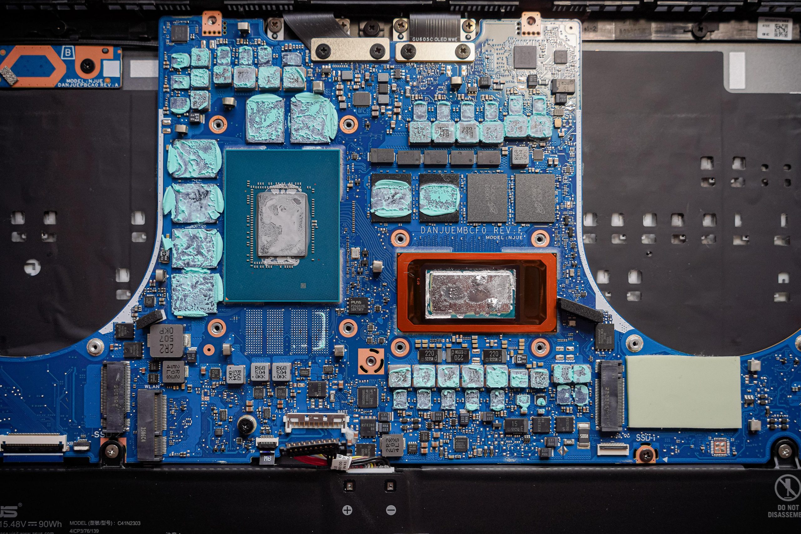 A close-up of a laptop motherboard with visible thermal paste on components and labeled with 'MODEL: NJUEC' and 'DANJUEMBCF0 REV: E' markings.