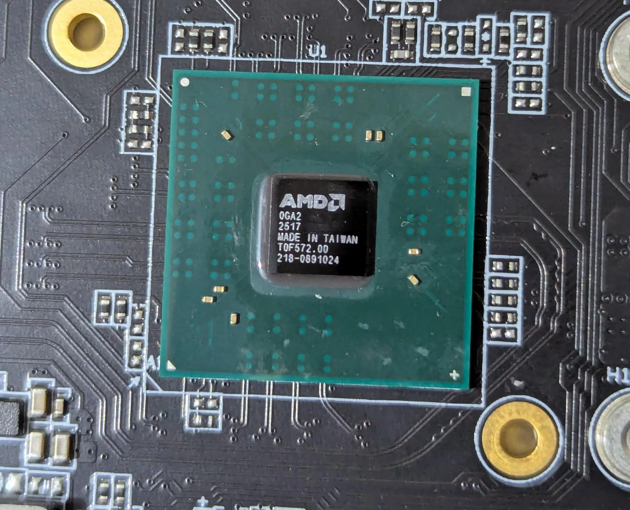 A close-up of an AMD chip labeled 'OGA2 2517 MADE IN TAIWAN TOF572.00 218-0891024' mounted on a circuit board.