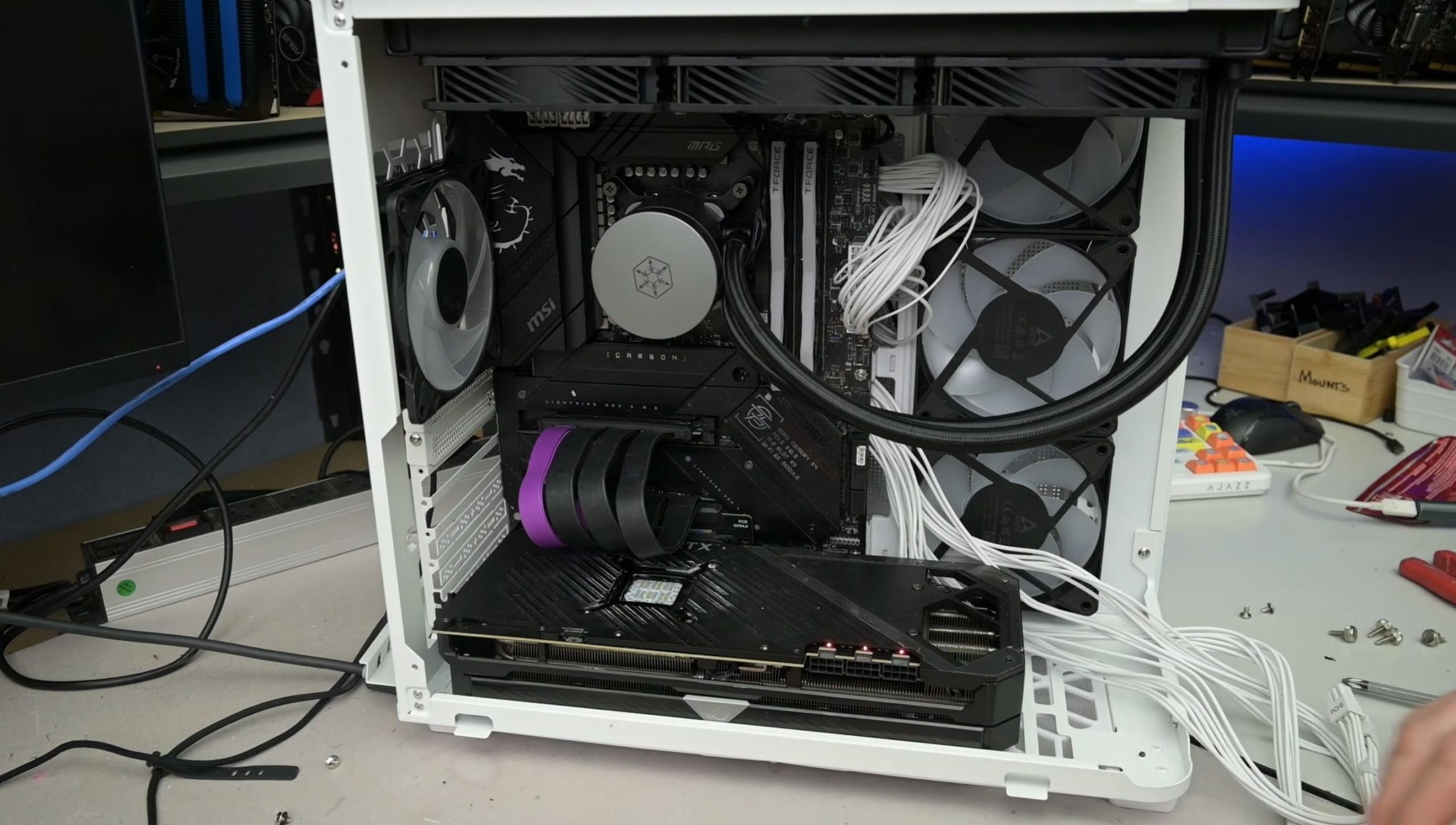 Intérieur d'un PC blanc avec une carte mère MSI MPG Z590 Gaming Carbon, une grande carte graphique, un refroidissement liquide SilverStone et de nombreux ventilateurs avec câbles tressés blancs.