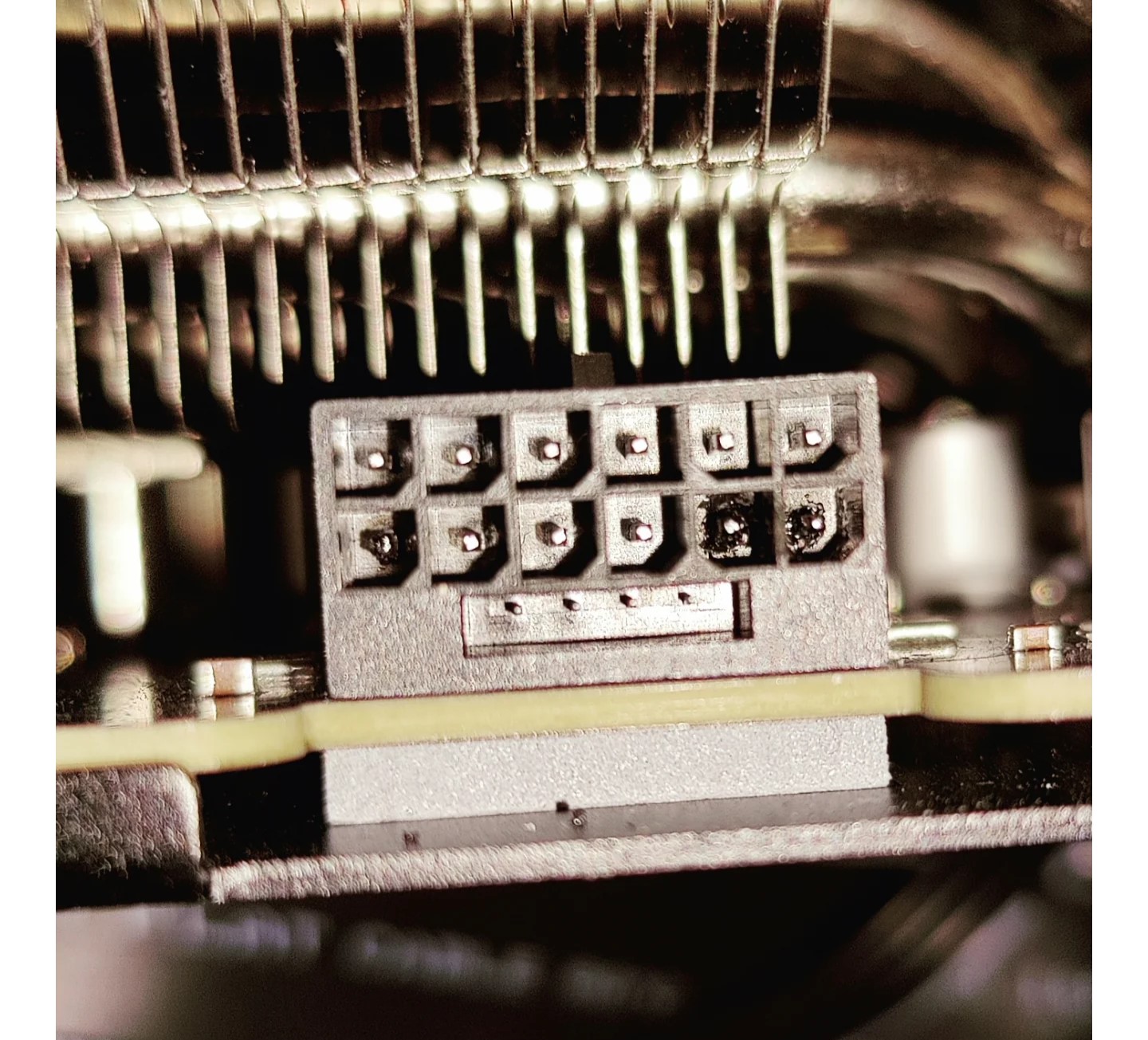 Un connecteur d'alimentation 12-pin de GPU avec des marques de brûlure visibles sur une broche.