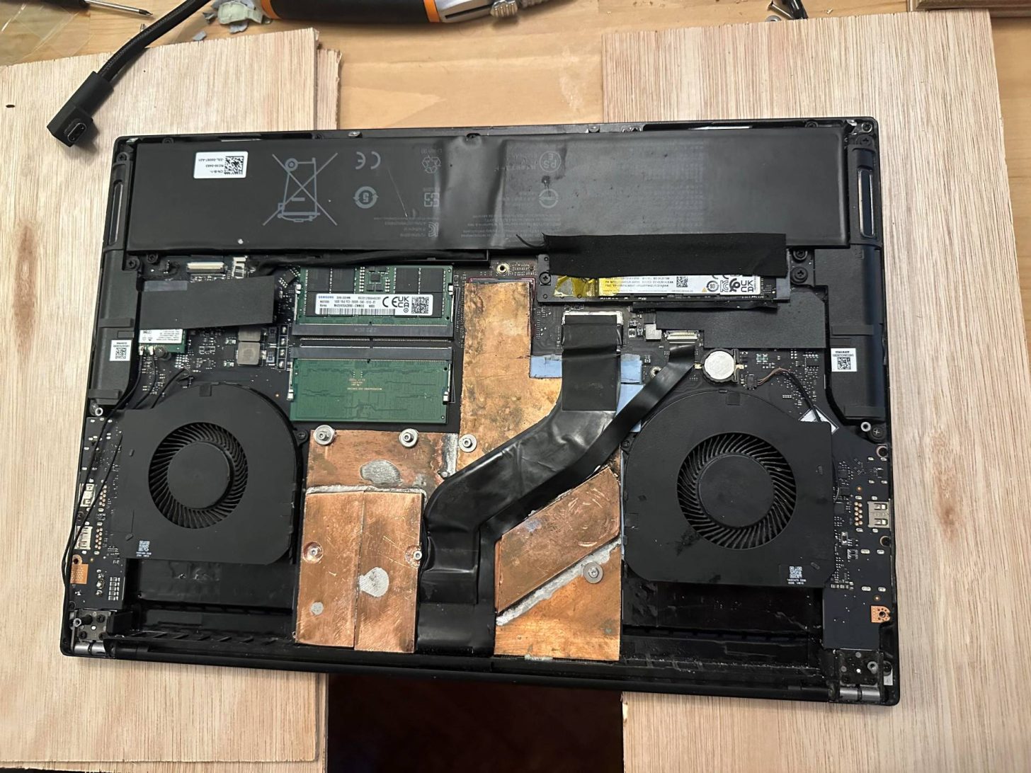 Le dessous d'un Razer Blade 16 ouvert, montrant les ventilateurs, la batterie, les barrettes RAM et les nouveaux radiateurs en cuivre.