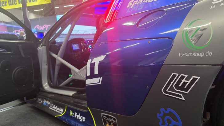 L'intérieur d'une voiture de course avec des logos de sponsors, présenté dans un espace d'exposition avec éclairage néon.